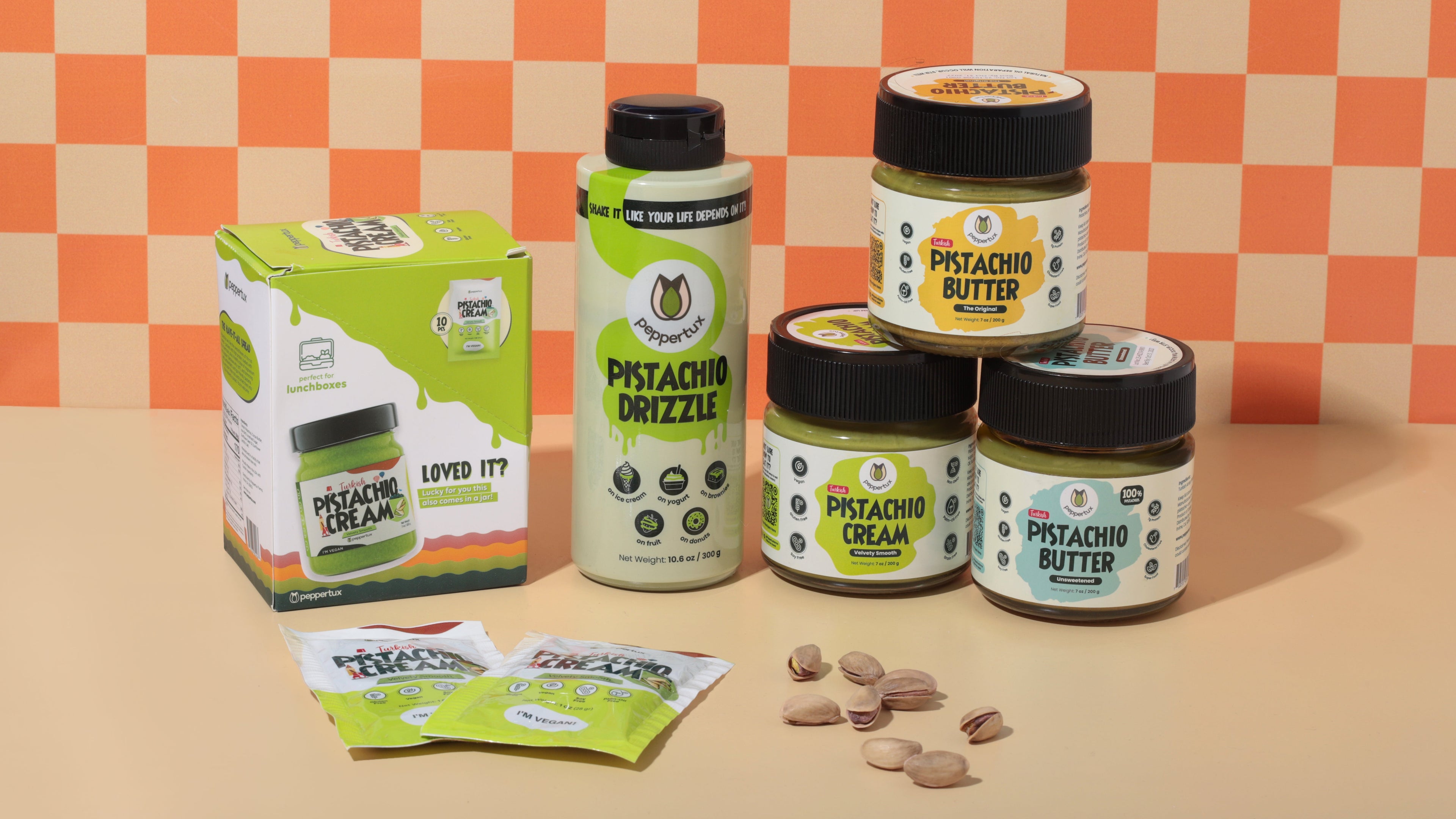 Assorted jars of Peppertux Pistachio Butter, Peppertux Pistachio Cream and Peppertux Pistachio Drizzle on a checkered background